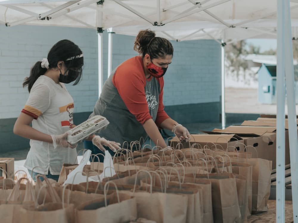 Volunteers packing donation bags under a canopy